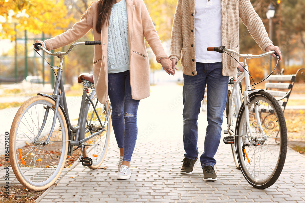 Obraz premium Young couple walking with bicycles in park