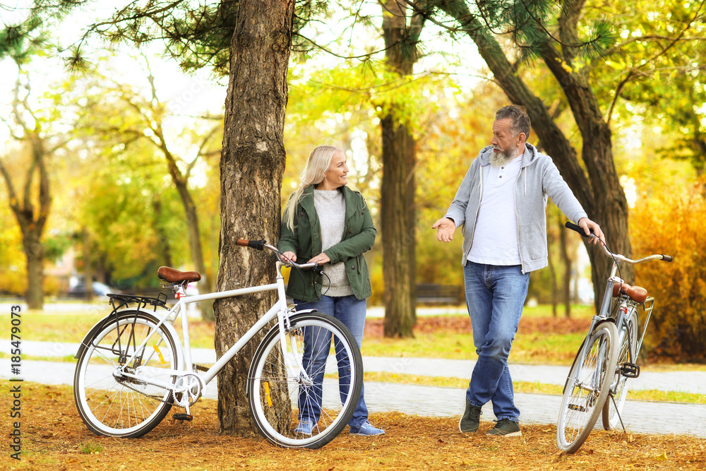 Senior couple resting after bike ride in park Senior couple resting after bike ride in park