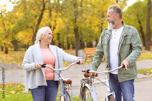 Senior couple walking with bicycles in park © Africa Studio