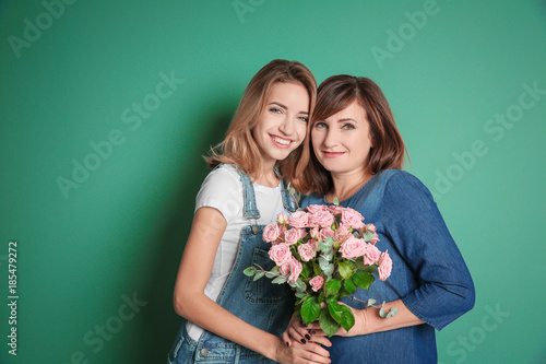 Attractive young woman with her mother on color background