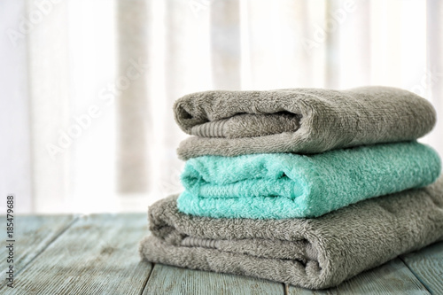 Stack of bath towels on table against light background © Africa Studio