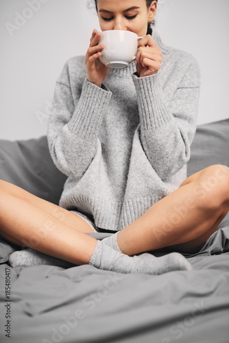 Portrait of woman drinking coffee in the morning while sitting on the bed photo