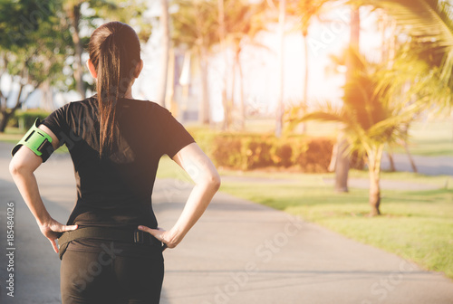 Back view of asian fitness woman standing before running on the outdoor workout in the park evening time.  Sport and Healthy Concept