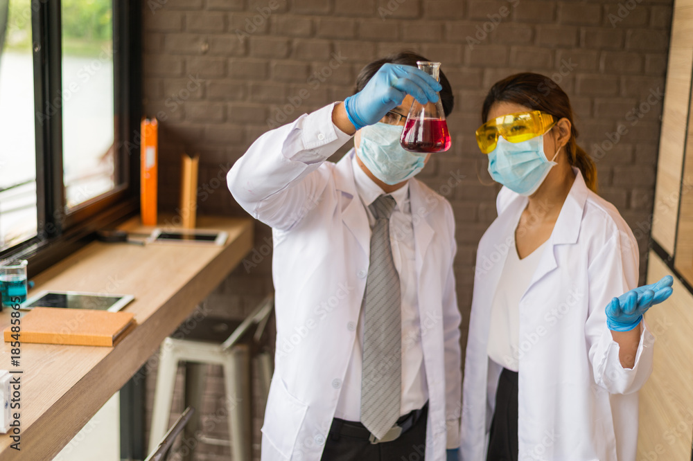 Fototapeta premium scientist man and woman wear white dress and blue gloves holding glass test tube. Chemist examines chemical test tube, science, doctor