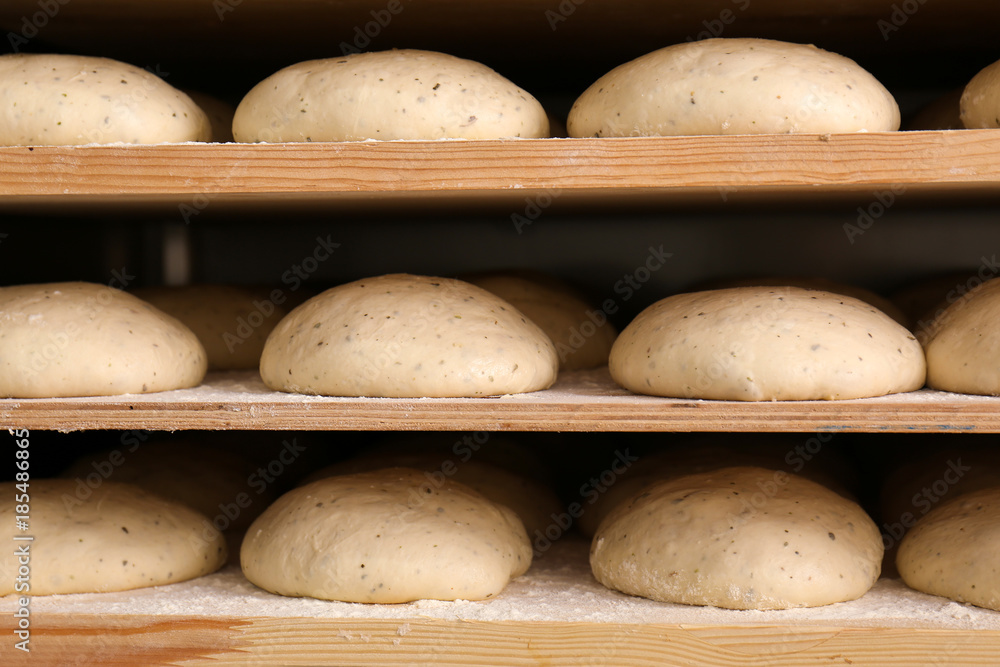 Raw loaves of bread on shelves in bakery Raw loaves of bread on shelves in bakery