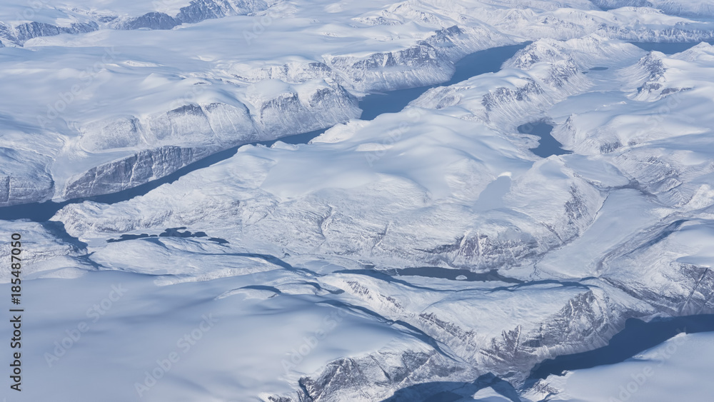 Aerial view of the glaciers and icebergs of Greenland from the window of an airplane passing by
