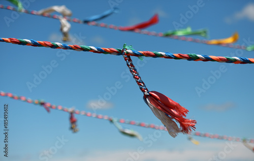 colorful prayer ropes and wind chimes fluttering in the wind and blue sky photo