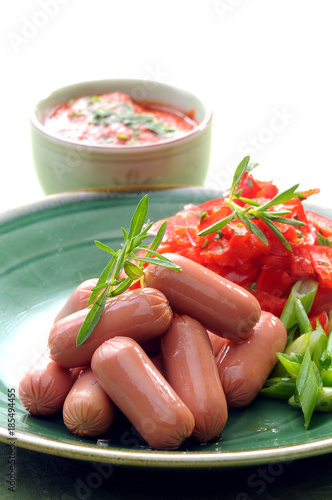 Chicken & Beef cocktail sausage with cherry tomato radish and lemon with green herb with toast bread on green red and bamboo background  with white and green plate