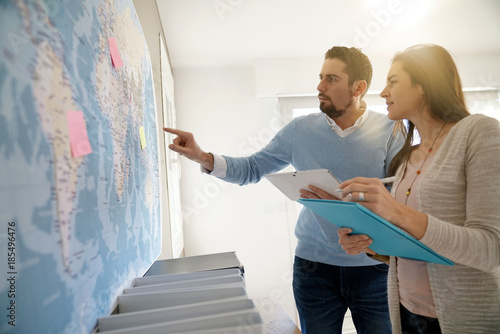 Colleagues in office looking at world map