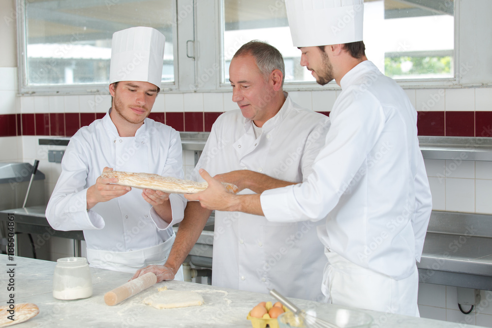 baker and his assistants working in kitchen