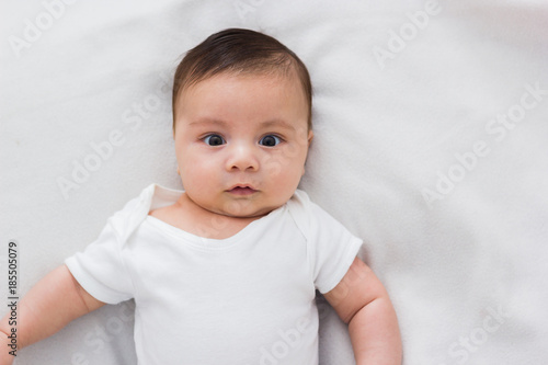 adorable baby lying on a bed of white sheets