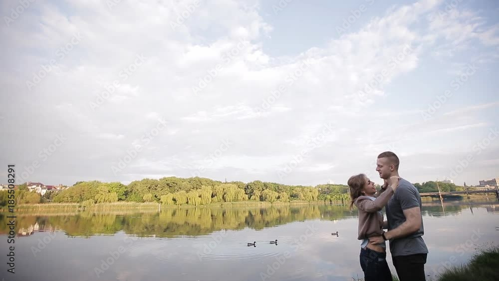 Lovers on a date by the river against the background of the city. A guy hugs a happy girl