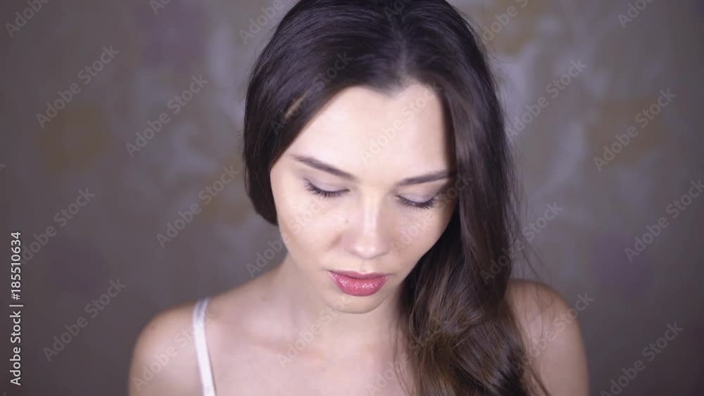 Face of sexy brunette close-up. A young woman with long curly hair puts a large white headset around her neck. Flirts with the camera. Artificial light sources. 4k Face of sexy brunette close-up. A young woman with long curly hair puts a large white headset around her neck. Flirts with the camera. Artificial light sources. 4k