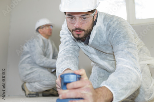 young carpenter sanding with electric sander