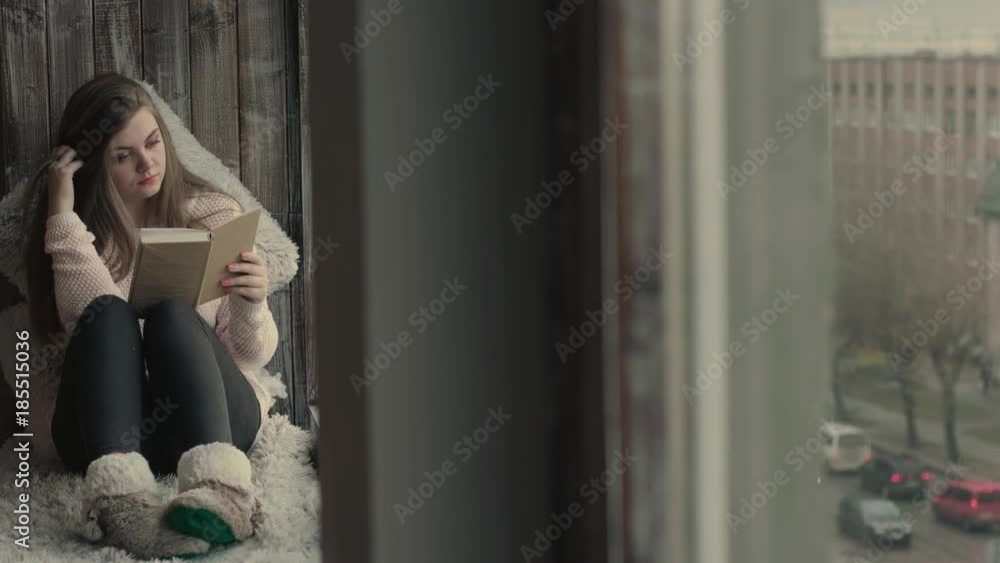 Beautiful young woman sitting on window and read a book Beautiful young woman sitting on window and read a book