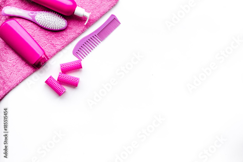 Basic hair care in bathroom. Comb, shampoo, spray, curlers, towel on white background top view copyspace