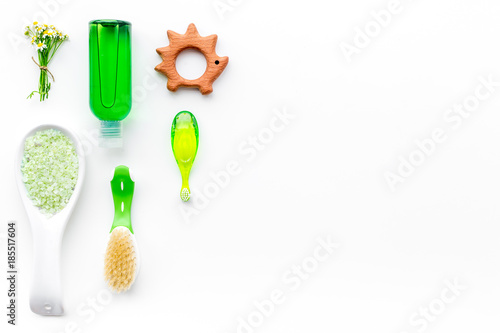 Soft bath cosmetics for kids with chamomile. Bottles, spa salt, tooth brush and toy on white background top view copyspace