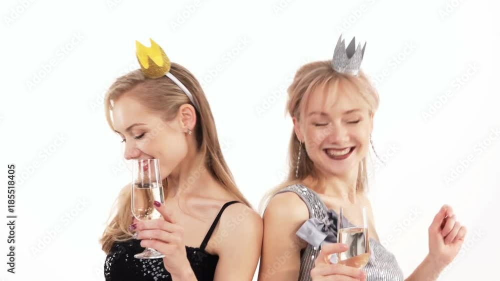 2 beautiful cheerful twin girls with glasses of champagne posing in the studio on a white background 2 beautiful cheerful twin girls with glasses of champagne posing in the studio on a white background
