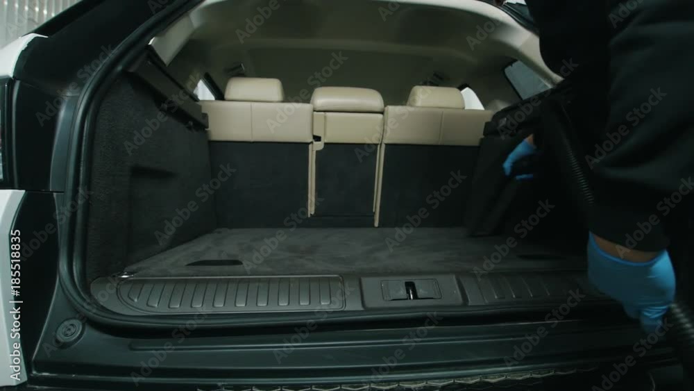 Man cleans the car interior with vacuum cleaner, dry cleaning of trunk Man cleans the car interior with vacuum cleaner, dry cleaning of trunk