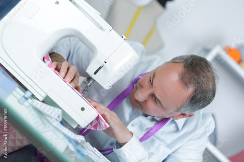 mature tailor working at sewing machine