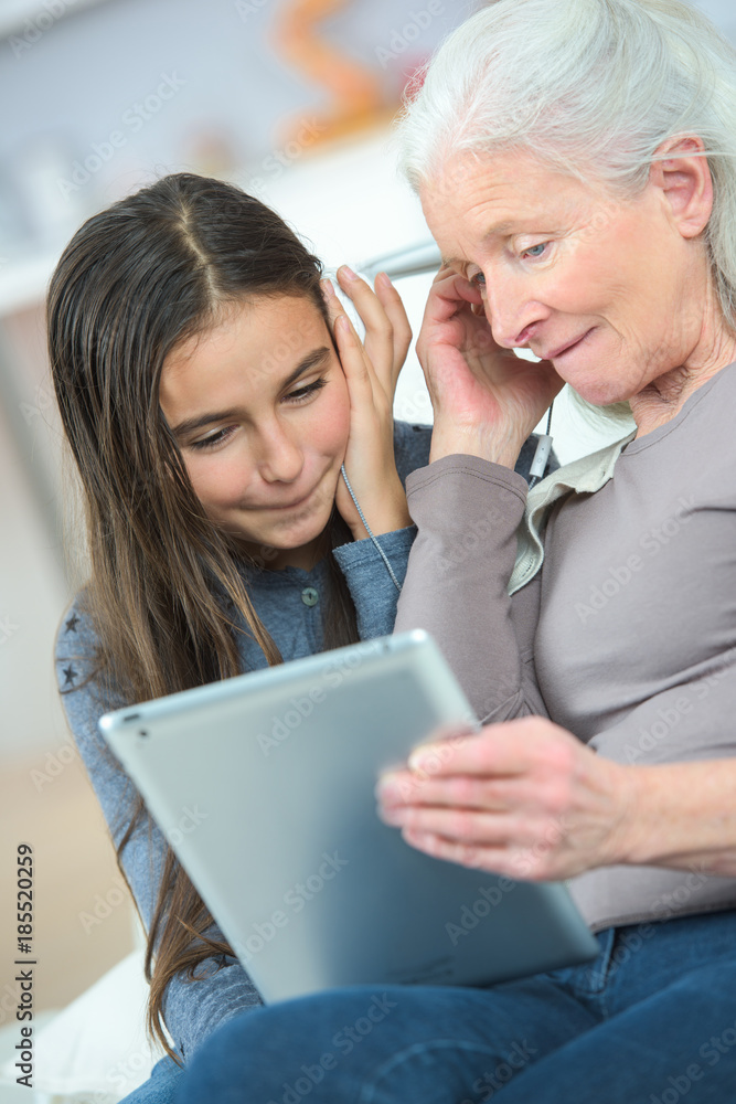 grandmother and granddaughter with tablet on sofa grandmother and granddaughter with tablet on sofa