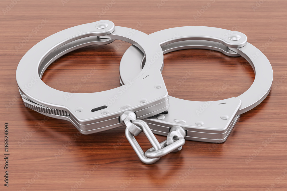 Obraz premium Handcuffs on the wooden table, 3D rendering