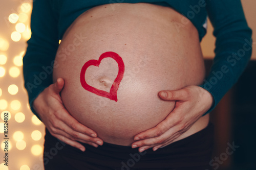 Wallpaper Mural young and beautiful mom to be posing at home with her big baby belly bump. concept of love for unborn child. red heart drawn across the pregnant belly. Torontodigital.ca