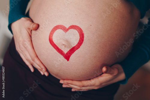 Wallpaper Mural young and beautiful mom to be posing at home with her big baby belly bump. concept of love for unborn child. red heart drawn across the pregnant belly. Torontodigital.ca