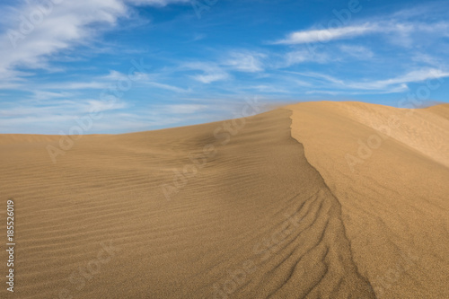 Sand in the Dunes of Maspalomas, a small desert on Gran Canaria, Spain. Sand blowing in the wind on top of the hill.