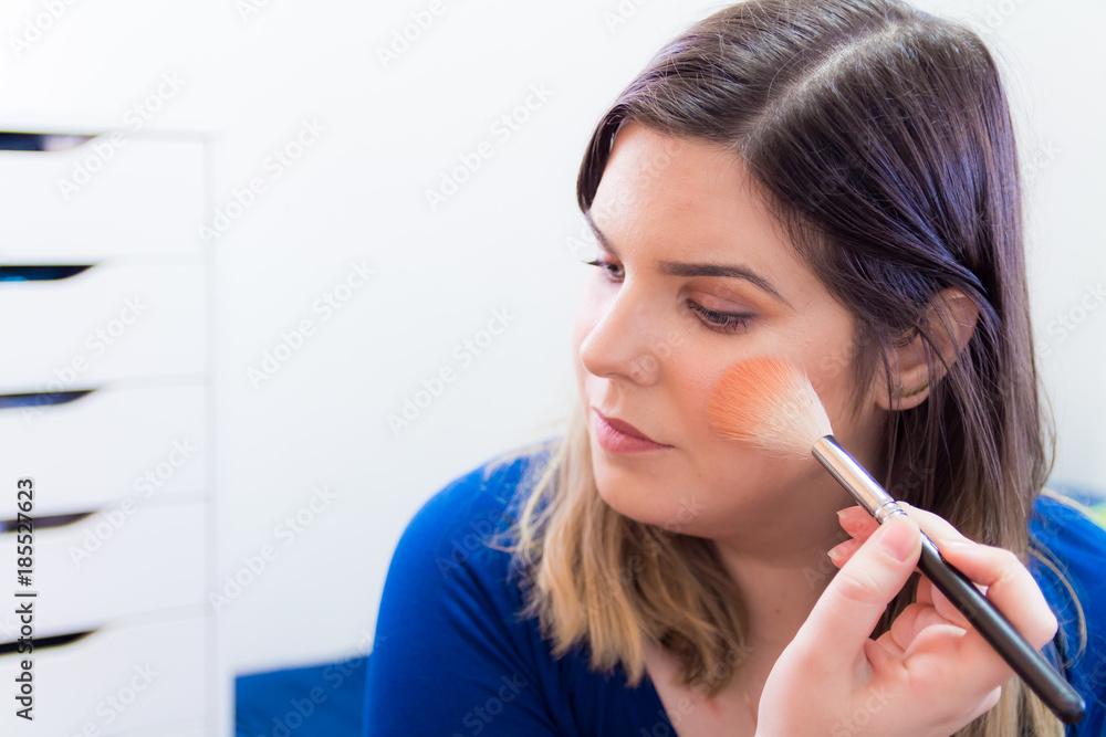 Woman applying makeup in her bedroom Woman applying makeup in her bedroom