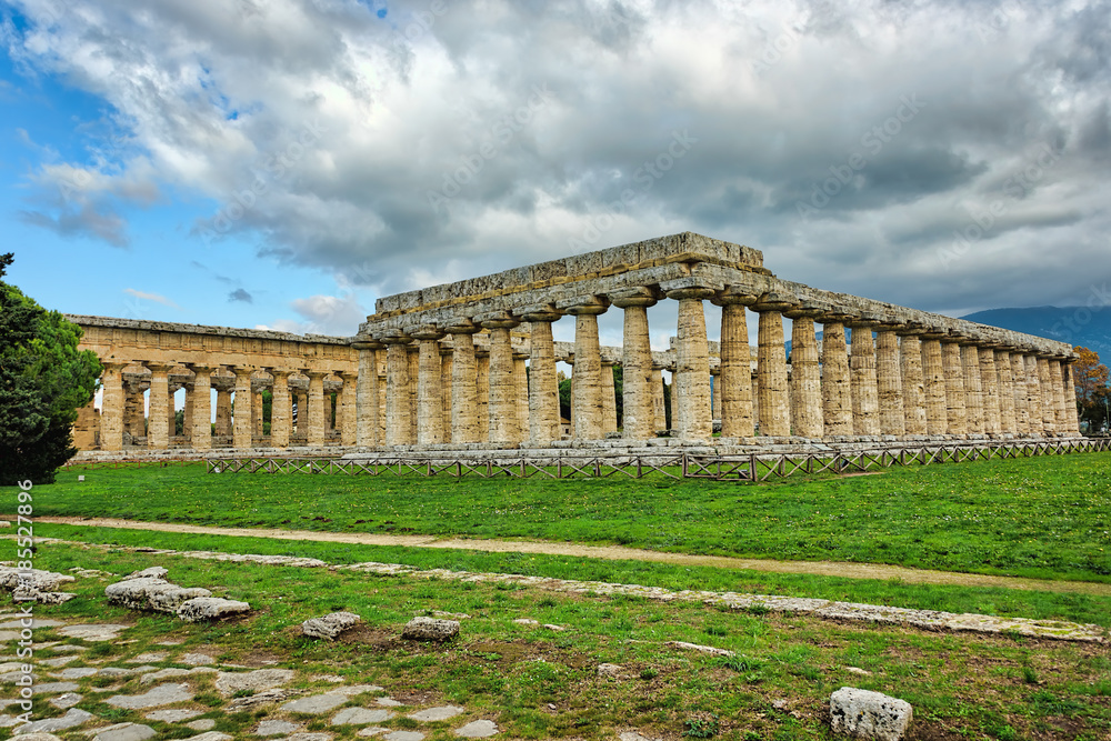 Greek temple in southern Italy on greenery under blue skies with
