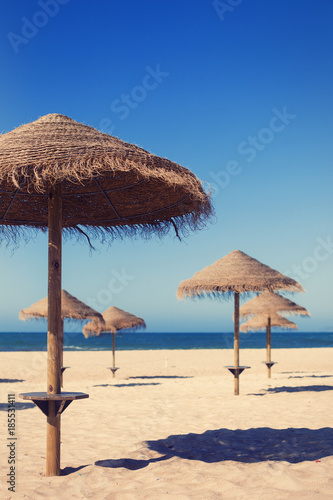 Beach umbrellas near blue ocean. Summer travel, vacation on sea shore