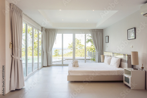 Modern bed room interior in Luxury villa. White colours, big window © Annatamila