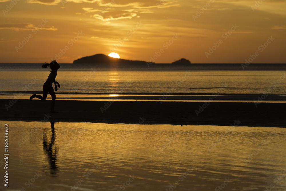 the silhouette photo of asian girl enjoy running on the beach with colorful sea in sunrise