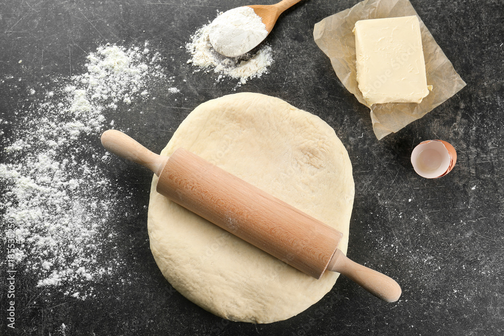 Raw dough with rolling pin on table Raw dough with rolling pin on table