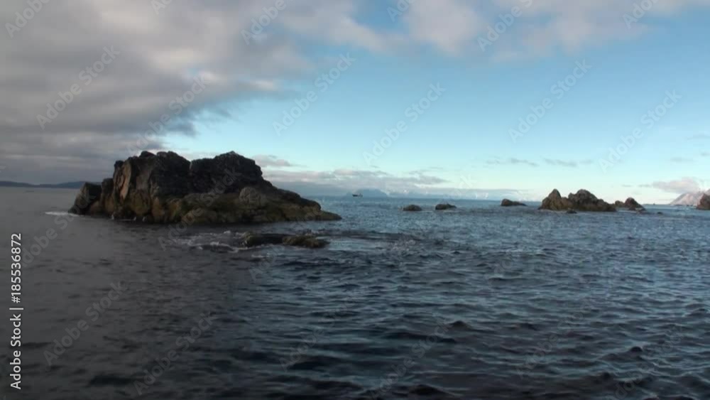 Stone rocks cliffs in water on background of Arctic Ocean in Svalbard. Wildlife in Nordic badlands. Natural landscape of Spitsbergen. Peace and quiet. Stone rocks cliffs in water on background of Arctic Ocean in Svalbard. Wildlife in Nordic badlands. Natural landscape of Spitsbergen. Peace and quiet.