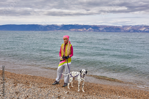 Dark clouds gathering over lake Baikal. A girl and a dog are walking along the coast. photo