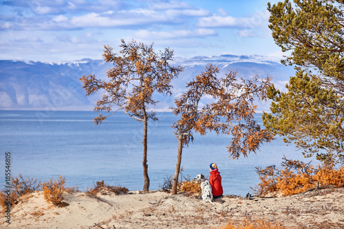Dark clouds gathering over lake Baikal. A girl and a dog are walking along the coast. photo