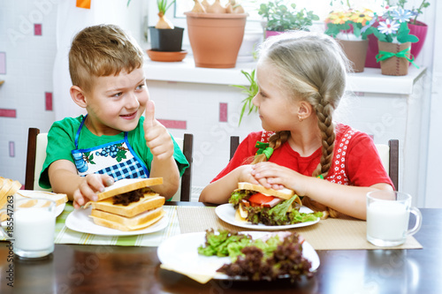 Children make sandwiches in the kitchen . Funny kids make sandwiches