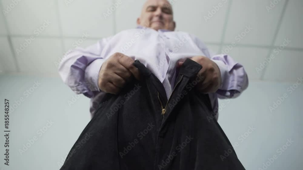 Base view of overweight man trying hard to zip tight pants, disappointment Base view of overweight man trying hard to zip tight pants, disappointment