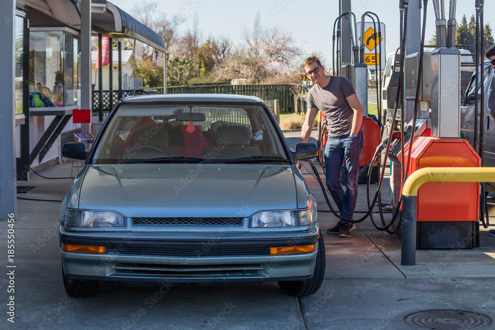 Young man fueling his car at gas station