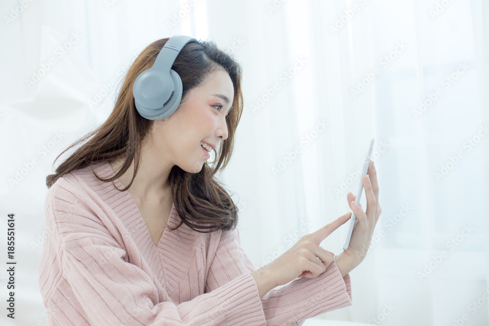 Attractive Asian Girl wearing sweater using a tablet at home. Woman with winter concept. Attractive Asian Girl wearing sweater using a tablet at home. Woman with winter concept.