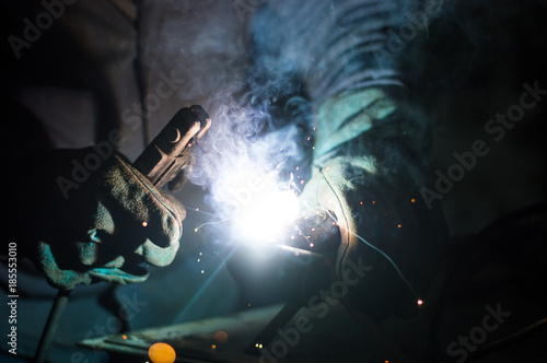 Fototapeta Naklejka Na Ścianę i Meble -  A man welds a metal with a welding machine