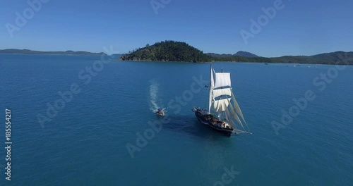 WHITSUNDAY ISLANDS – FEBRUARY 2016 : Aerial shot of motorboat moving up to sailboat / ship on a sunny day with amazing landscape and ocean in view photo