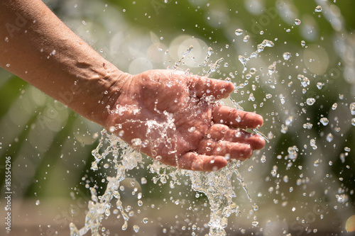 Hand of a man in a spray of water from a fountain