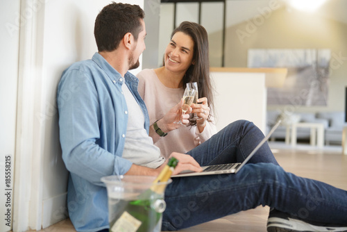 Couple cheering with champagne in new home