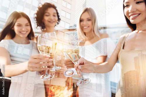 Alcoholic drinks. Selective focus of glasses with champagne being held by nice beautiful delighted women