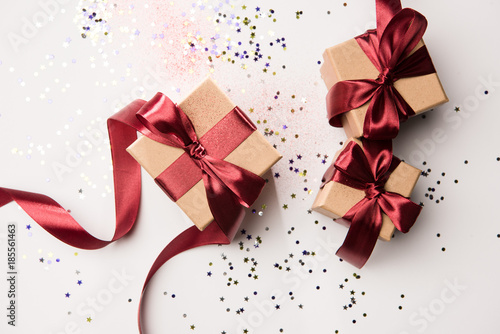 top view of arranged gifts with red ribbons and confetti isolated on white