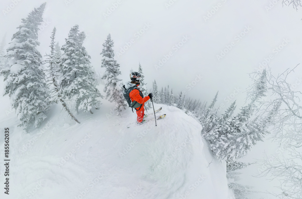 Man skier freerider standing at top of ridge, adventure winter freeride extreme sport