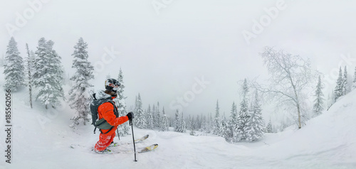 Man skier freerider standing at top of ridge, adventure winter freeride extreme sport